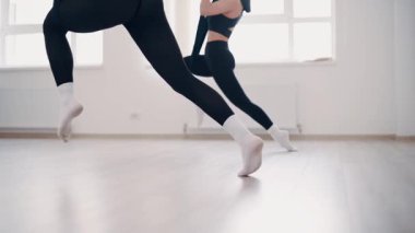 İnce vücutlu iki kız spor salonunda esnek kumaş üzerinde egzersiz yapıyor. Yavaş çekim.