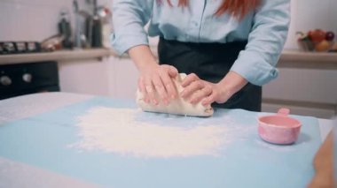 Bir kadın para kazanır. Şef mutfaktaki masada hamur yoğuruyor. Ellerin yakın çekimi.