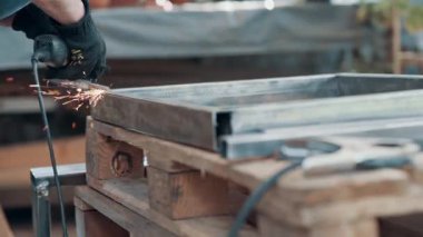 Kaynaklanmış eklemlerin öğütülmesi. Bir adam, metal bir ürünü, bir açı öğütücüyle işliyor. Yakın plan..