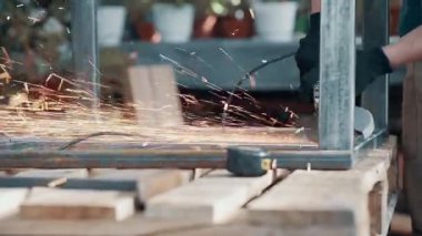 Kaynaklanmış eklemlerin öğütülmesi. Bir adam, metal bir ürünü, bir açı öğütücüyle işliyor. Yakın plan..