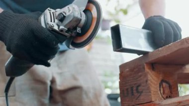 Bir adam, metal bir ürünü, bir açı öğütücüyle işliyor. Yakın plan..