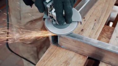 Kaynaklanmış eklemlerin öğütülmesi. Bir adam, metal bir ürünü, bir açı öğütücüyle işliyor. Yakın plan..