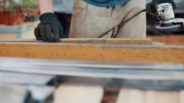 Bir işçi, çelik bir parçanın pasını öğütücüyle öğütüyor. Yakın plan..