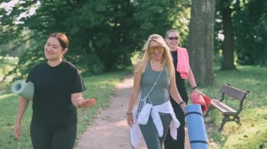 Üç orta yaşlı kadın parkta yoga dersinden sonra birlikte yürüyorlar..
