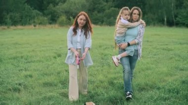 Friends are walking in nature. Two adult women and a child walking in the park with a pug dog. 