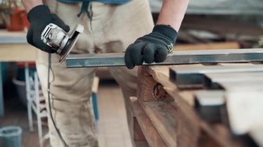 Kaynaklanmış eklemlerin öğütülmesi. Bir adam, metal bir ürünü, bir açı öğütücüyle işliyor. Yakın plan..