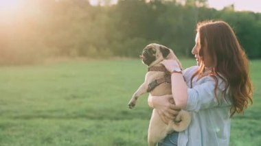 Genç bir kadın dışarıda sevgili köpeğini okşar ve ona sarılır..