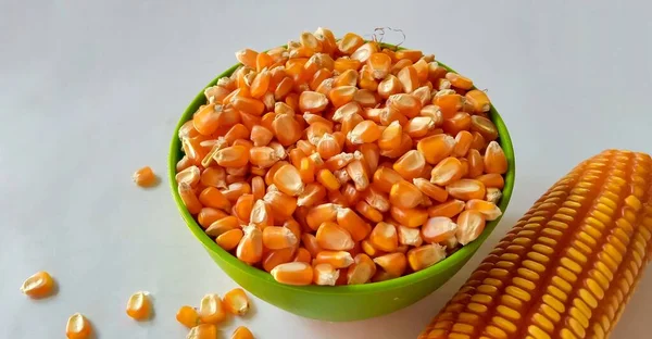 Close-up of dry corn in bowl on a white background.
