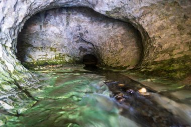 Rock tunnel with streaming river, nature landscape