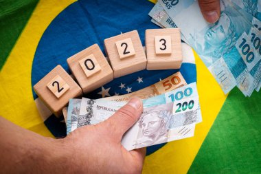 2023 yılına karşı Brezilya bayrağının arkaplanı, para dolu eller, Kavram, Brezilya 'nın 2023' teki ekonomik umutları, ekonomik büyüme ve ülkede değişim umutları
