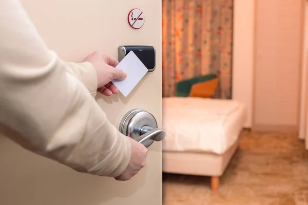 A woman opens a hotel room door with an access card