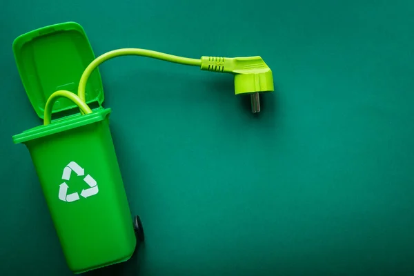 Green cable sticking out of a recycling bin, Environmental concept, Renewable energy, Copy space, green color, Modern energy sources
