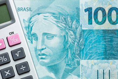 Brezilya parası, 100 reais banknot ve hesap makinesi, finansal hesaplama kavramı