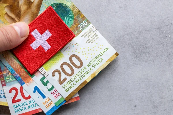 Swiss money and national emblem held in hand, Gray background, copy space, flay lay, Financial background