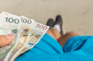 Oturan genç bir çocuk 800 Polonyalı zlotiyi rahatça elinde tutuyor. Polonya, finansal konsept, sosyal program 800 artı, her çocuk için PLN 800 yardım artışı