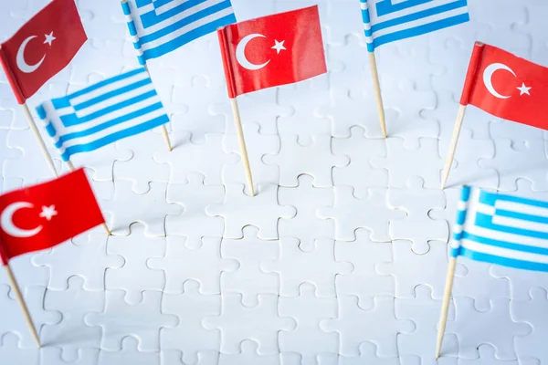 miniature flags of greece and turkey sticking out of white puzzle pieces, The concept of mutual relations between the two countries, Empty space