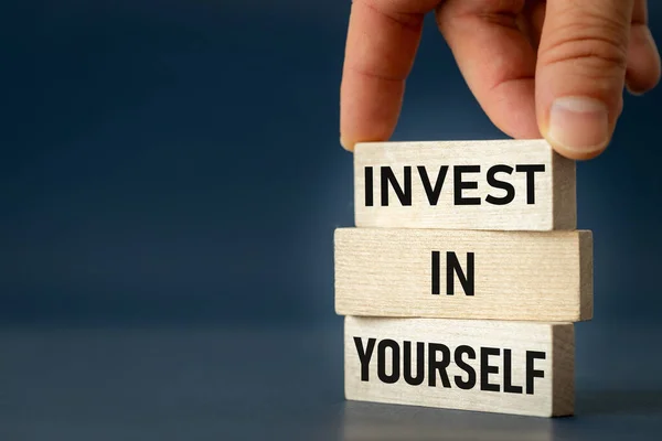 Invest in Yourself, hand arranging wooden blocks to form a slogan, Invest in Yourself, copy space, the concept of development and the pursuit of self-realization in life and business