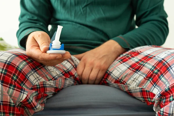Urology, problems with urination in men. Health concept, A man in pajamas holds a catheter in his hand to help with peeing