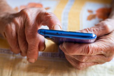 Yaşlı bir bayan, bir emekli, akıllı bir telefondan bakıyor, konsept, yeni teknolojilerle ilgilenen yaşlılar