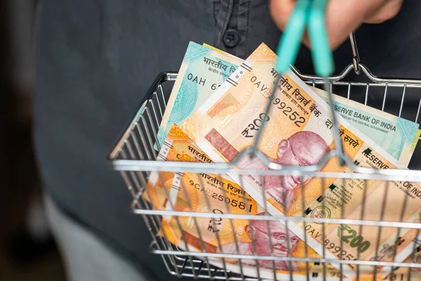India Money in Shopping Cart. A man holding a basket of Indian rupees in his hand, financial and economic concept. Rising prices, falling purchasing value of money in India
