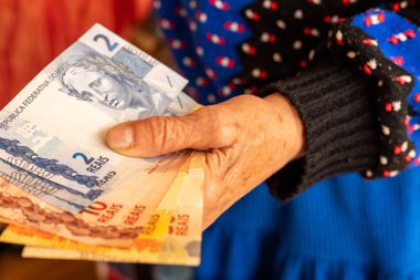 Brezilya parası, bir emekli elinde çeşitli reais banknotları, yaşlıların mali sorunları, Brezilya 'da düşük emekli maaşları