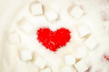 Sağlıkla ilgilenmek, tatlı yemenin olumsuz etkisi, sağlıklı yaşam tarzı kavramı, beyaz şeker küpleri arasında yatan kalp, aşırı kilolu ve diyabet