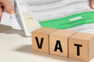 Polonya 'da KDV anlaşması, katma değer vergisinin kısaltması, satıcılar ve alıcılar tarafından ödenen mal ve hizmetlere uygulanan vergi, maliye kavramı, ahşap bloklar ve tutulmuş belge yığını ve bürokrasi üzerine yazılmış.