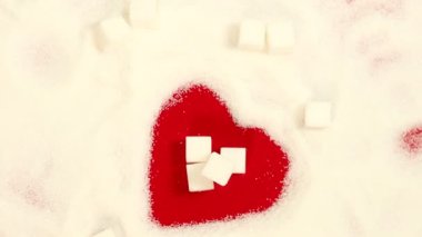 Şekerin sağlık üzerindeki olumsuz etkisi, sağlıklı yaşam tarzı kavramı, beyaz şeker ile çizilen kırmızı kalp, içinde dönen şeker küpleri,