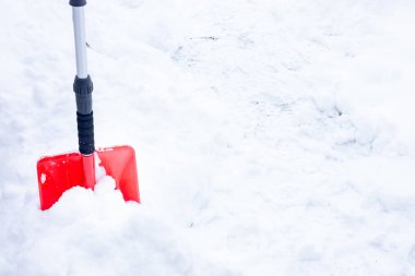 Kışın kar temizleme, kar yağışı, karda yatan kırmızı kürek. Mevsimsel konsept, zor hava koşulları