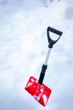 Kışın kar temizleme, kar yağışı, karda yatan kırmızı kürek. Mevsimsel konsept, zor hava koşulları