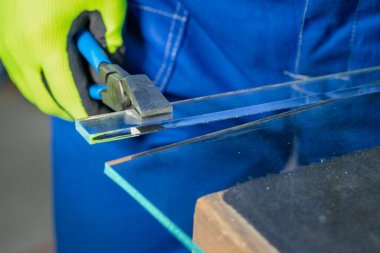 Bir camcı, cam fabrikasında çalışan özel bir şalter kullanarak küçük kalın bir cam parçasını elle kırarak kapatır.