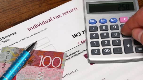 ニュージーランド コンセプト オフィスとの納税 税形態 男は計算機による税金を計算し ニュージーランドドルの積み重ね — ストック動画