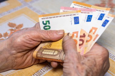 Euro bölgesi ülkelerindeki yaşlı insanların ev bütçesi. Ekonomik konsept, emekli kadının elinde 50 ve 10 avroluk banknotlar, yaşlıların mali durumu