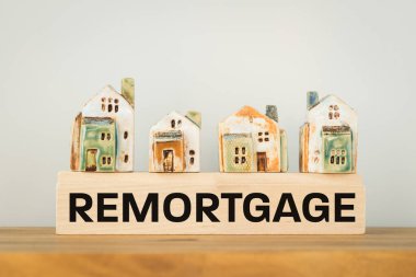 REMORTGAGE, a word written on a wooden block with miniature houses. Real estate business and financial concept, copy space clipart