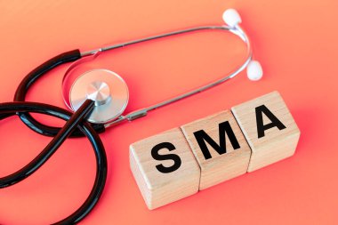 SMA hastalığı sembolü, omurilik kasları körelmesi, tahta bloklara yazılmış tıbbi steteskop, sağlık konsepti, kopyalama alanı.