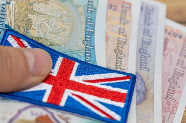 Büyük Britanya parası, büyük İngiliz bayrağı ve İngiliz poundu el ele, yakın plan, finans sektörü konsepti, İngiltere para birimi