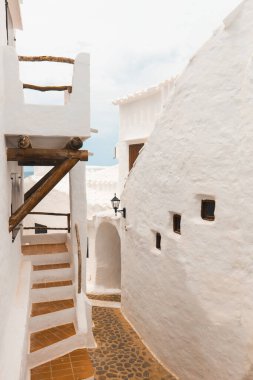 The charming town of Binibeca on Menorca. Narrow streets and white walls of houses with wooden elements, Mediterranean architecture, wonderful Spain. clipart