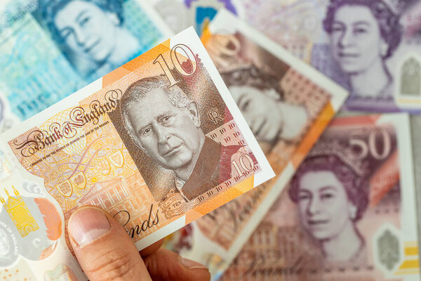 New Banknote с портретом короля Карла III, впервые выпущенным в июне 2024 года Банком Англии, Великобритания. На заднем плане старые банкноты с изображением королевы