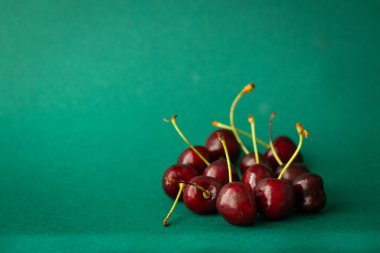 Lezzetli ve sağlıklı kirazlar. Koyu yeşil bir zemin üzerinde vitamin dolu olgun meyveler.