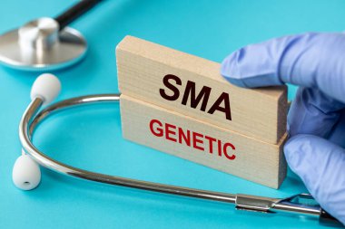 SMA hastalığı, Doktor SMA Genetik sözleriyle tahta bloklar gösteriyor. Omurilik kasları körelmesi. Doktorun steteskobu, güzel mavi arka plan. Sağlık kavramı