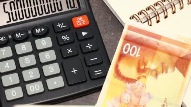 İşadamı bir iş defterinin arka planında İsrailli şekelleri sayıyor. Finansal konsept, İsrail parası