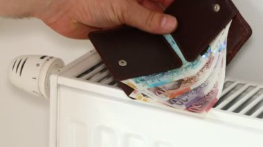 İngiltere. İngiltere 'de enerji fiyatları artar. Ekonomik ve finansal konsept. İngiliz sterlini vidalanmamış bir radyatörün üzerinde yatıyor.