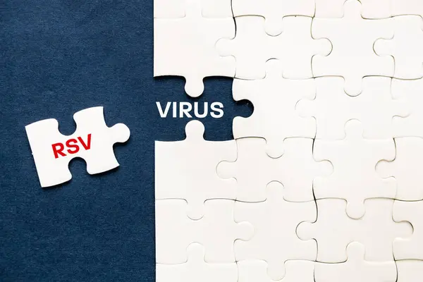 stock image Virus RSV Respiratory Syncytial Virus. A piece of a puzzle removed revealing the word Virus RSV. Medical concept. Seasonal flu, health care, Navy background, Copy space