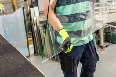 Cam fabrikasındaki bir camcı, büyük bir cam parçasını elinde tutar, cam işçiliği ve endüstri konsepti,