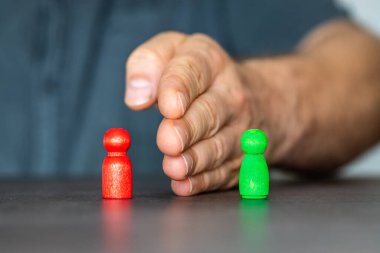 İki ahşap figür arasında el ele tutuşan kişi. Yumuşak beceriler ve çatışma çözümü kavramı.