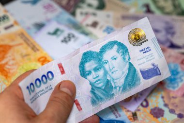 Arjantin parası, 10.000 Arjantin pezosu diğer mezheplerin arka planına karşı el ele tutuştu