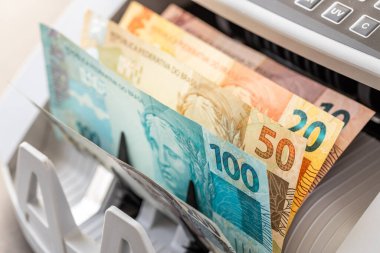 Brezilya parası. Brezilyalı banknotlar çevirme makinesinde. Finansal iş konsepti, kapat
