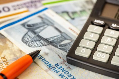 Danimarka 'dan gelen para, finansal analiz, ev bütçesi, vergi hesapları, finansal konsept. Hesap makinesi ve kalemi olan Danimarka kronu