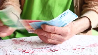 Yaşlı bir kadın elinde bir kaç banknot tutuyor. Norveç kron parası, finansal konsept. Norveç 'teki emeklilerin enflasyon ve mali sorunları