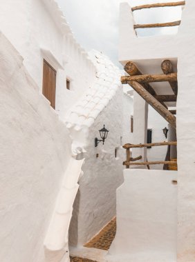 The charming town of Binibeca on Menorca. Narrow streets and white walls of houses with wooden elements, Mediterranean architecture, wonderful Spain. clipart